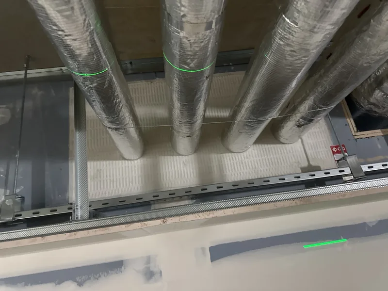 Several insulated pipes passing through a batt-sealed opening above a ceiling